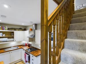 uma cozinha com armários brancos e uma escadaria em Stoneswood Cottage & Garden, Delph, Saddleworth em Delph