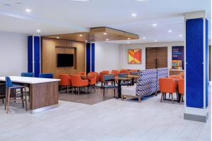 a waiting room with tables and chairs and a tv at Holiday Inn Express La Mesa Near SDSU, an IHG Hotel in La Mesa