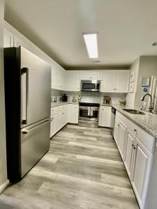 a kitchen with white cabinets and a stainless steel refrigerator at Cozy Corner - Family Beach Vacation Condo in Wilmington