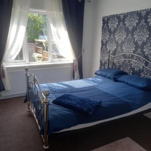 um quarto com uma cama com lençóis azuis e uma janela em Jolly Piece em Castleford