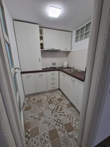 Una cocina con gabinetes blancos y piso de baldosas. en Bran Studio, en Bran