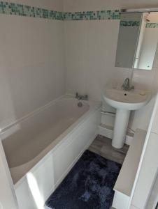 ein Badezimmer mit einer weißen Badewanne und einem Waschbecken in der Unterkunft 3 Bedroom Apartment with Golf Course View in Newcastle upon Tyne
