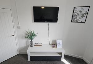 a room with a white table and a tv on a wall at Contemporary Highland Cottage in Invergordon