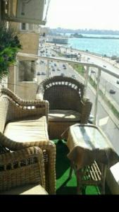 2 Korbstühle und ein Tisch auf dem Balkon in der Unterkunft شقه للإيجار المفروش سوبر لوكس (vip) أمام البحر مباشرة in Alexandria