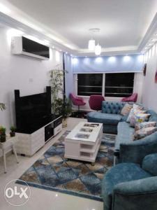 ein Wohnzimmer mit einem blauen Sofa und einem TV in der Unterkunft شقه للإيجار المفروش سوبر لوكس (vip) أمام البحر مباشرة in Alexandria
