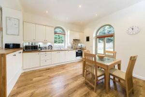 cocina con armarios blancos y mesa de madera en Folly - Middleton Hall Estate en Belford