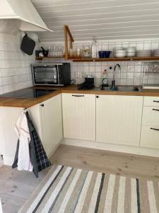 a kitchen with white cabinets and a black microwave at Historisk Charm i Hjärtat av Gamla Stan Kalmar in Kalmar