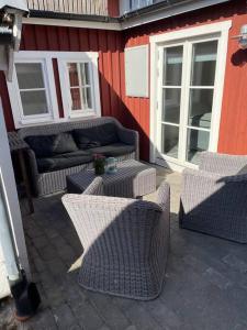 eine Terrasse mit Korbstühlen, einem Sofa und Fenstern in der Unterkunft Historisk Charm i Hjärtat av Gamla Stan Kalmar in Kalmar