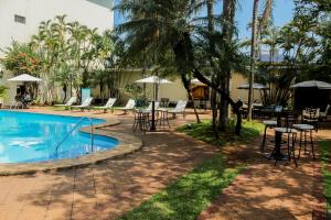 a pool with tables and chairs next to a building at Nobile Suites Excelsior Asuncion in Asuncion