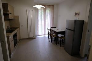 cocina con nevera, mesa y sillas en Casa Celeste, en Nocera Umbra