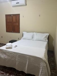 a bedroom with a white bed with a wooden door at CASA DE PRAIA CAJUEIRO ALTER in Alter do Chao