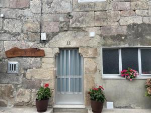 a stone building with two potted plants next to a door at A Casa da Torre Peruscallo in Belante