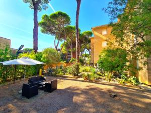 eine Terrasse mit einem Sonnenschirm, einem Tisch und Stühlen in der Unterkunft Casa Pineta in Principina a Mare