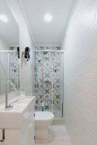 a white bathroom with a toilet and a shower at Casa do Azulejo II in Setúbal