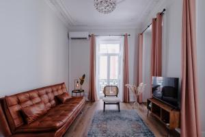 a living room with a brown leather couch and a television at Casa do Azulejo II in Setúbal