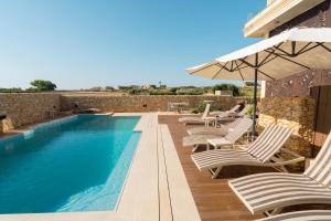 a swimming pool with lounge chairs and an umbrella at Santa Lucia Boutique Hotel in Santa Luċija
