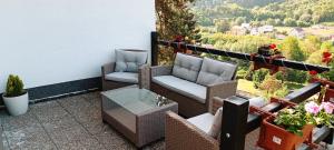 a balcony with wicker chairs and a glass table at Prostorný apartmán v CHKO Křivoklátsko 