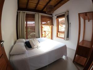 um quarto com uma cama branca e 2 janelas em Vila Bombaça - 100 metros da praia em Barra Grande
