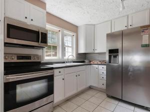 cocina con armarios blancos y nevera de acero inoxidable en The Great Escape - Lakefront Rental with Views en Inman