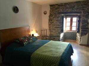 een slaapkamer met een bed en een stenen muur bij Casa da Forxa, renovated former forge/ smithy in Lugo