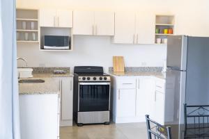 a kitchen with white cabinets and a stove top oven at Condominios Akira in Tamarindo +10 photos