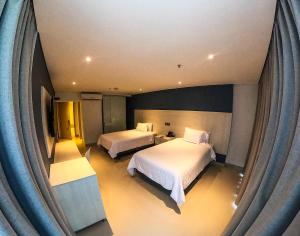 Habitación de hotel con 2 camas y ventana grande. en HOTEL MANZUR en Barranquilla