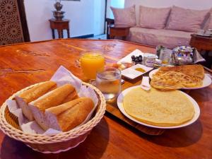 a table with two baskets of bread and orange juice at Riad Sibari in Meknès