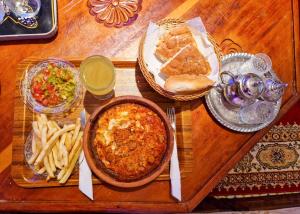 een houten tafel met een bord eten en frietjes bij Riad Sibari in Meknès