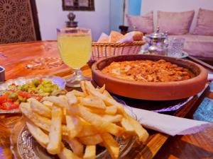 una mesa con un plato de papas fritas y un tazón de comida en Riad Sibari en Meknès