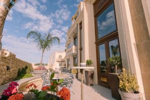 a building with a patio with chairs and flowers at Santa Lucia Boutique Hotel in Santa Luċija