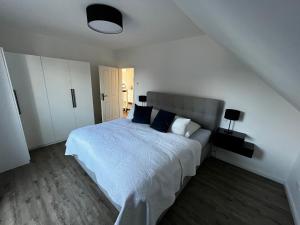 a white bedroom with a bed with blue pillows at Hochwertiges Haus mit Garten mit guter Anbindung in Berlin
