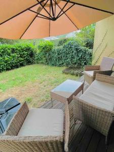 un patio con sillas, mesas y una sombrilla en Charmant studio avec jardin, en Eysines