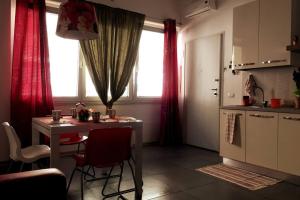 une cuisine avec une table et une fenêtre avec des rideaux rouges dans l'établissement Loft con ampia terrazza a 500 MT da Piazza Bovio., à Piombino