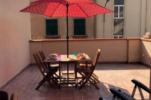 - une table et des chaises avec un parasol rouge sur la terrasse dans l'établissement Loft con ampia terrazza a 500 MT da Piazza Bovio., à Piombino