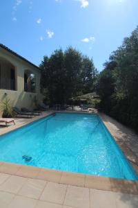 - une piscine d'eau bleue en face d'une maison dans l'établissement joli studio indépendant avec kitchenette, à Sauveterre