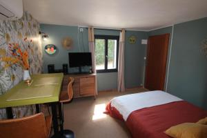 um quarto com uma cama, uma secretária e uma televisão em joli studio indépendant avec kitchenette em Sauveterre