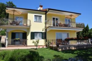 Casa amarilla con balcones y mesas en Apartments Sandra, en Brseč