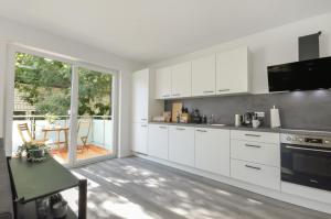 a kitchen with white cabinets and a large window at Stilvolle Stadtoase - Balkon - Parkplatz in Steinhagen