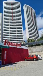 una macchina rossa parcheggiata in un parcheggio con due edifici alti di Ponta Negra RN03 a Natal