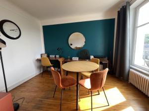 a dining room with a table and chairs and a clock at -Pause Retro- T2 Centre Gare Wifi Lave Linge in Quimper