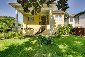 een geel huis met een veranda en een gazon bij Great New Orleans Condo - 4 Miles from Downtown! in New Orleans