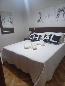 ein weißes Bett mit schwarzen und weißen Kissen darauf in der Unterkunft CASA ESQUILAS in Avila