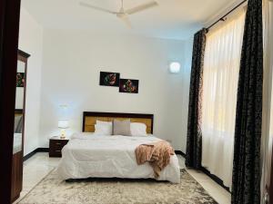 a bedroom with a large bed and a window at Lomes cozy home in Dar es Salaam