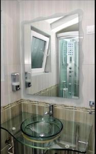 een badkamer met een glazen wastafel en een spiegel bij Villa Mare Apartments in Tivat