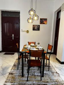una sala da pranzo con tavolo, sedie e lampadario pendente di Lomes cozy home a Dar es Salaam
