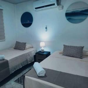 a room with two beds and a table with a lamp at Apartamentos Mar & Arena in San Andrés