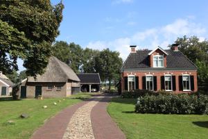 une maison avec un toit de chaume et une allée en briques dans l'établissement Galerie23noordsleen, à Noord-Sleen