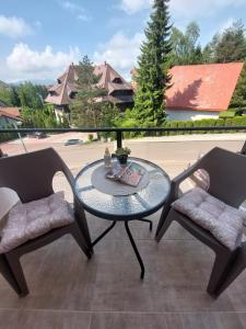 uma mesa de vidro e 2 cadeiras numa varanda em Apartman Stevanovic Zlatibor em Zlatibor