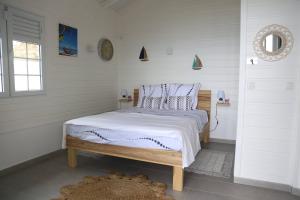 una camera da letto con un letto con pareti bianche e una finestra di Bungalow Palbéa supérieur avec SPA et vue mer a Schœlcher