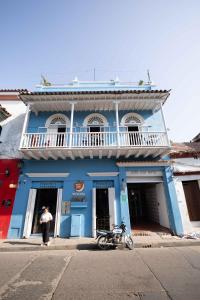 um homem parado na porta de um edifício azul em Media Luna Hostel Cartagena em Cartagena das Índias